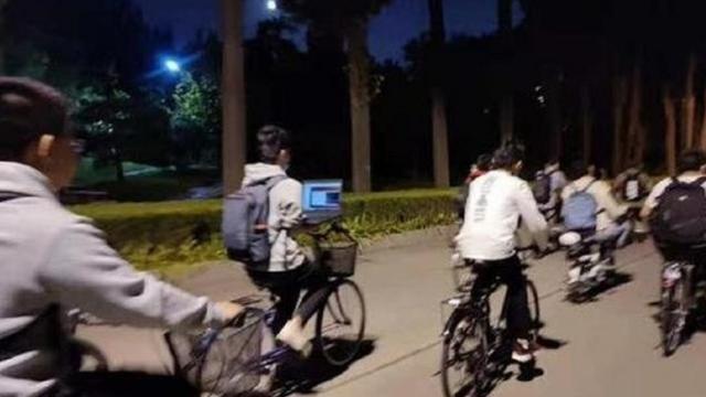Un estudiante de la Universidad Tsinghua opera su computador portátil mientras monta en bicicleta.