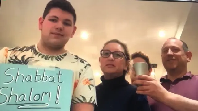 Family holding a sign reading Shabbat Shalom