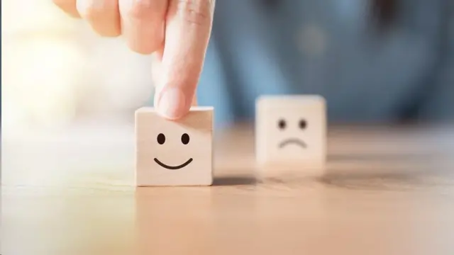 Un cubito de madera con una cara feliz y otro con una cara triste