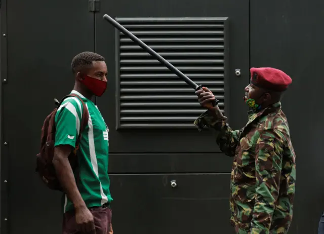 Un policía cuestiona a un transeúnte en un retén de control contra coronavirus en Kenia