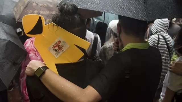 香港“反送中”示威“8·18流水式集会”群众举起黄色雨衣人像纸牌冒雨前行（8/8/2019）