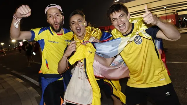 Tres fanáticos de Ecuador vestidos con la camiseta de la selección y arengando a la cámara.