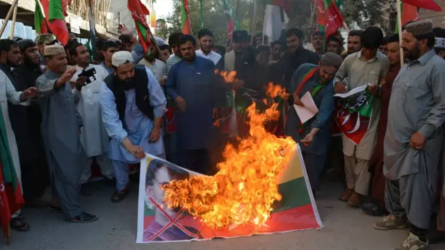 Pakistani Muslims burn the flagf of Myanmar flag with a picture of Aung San Suu Kyi during a protest against the Myanmar government for the treatment of Rohingya Muslims