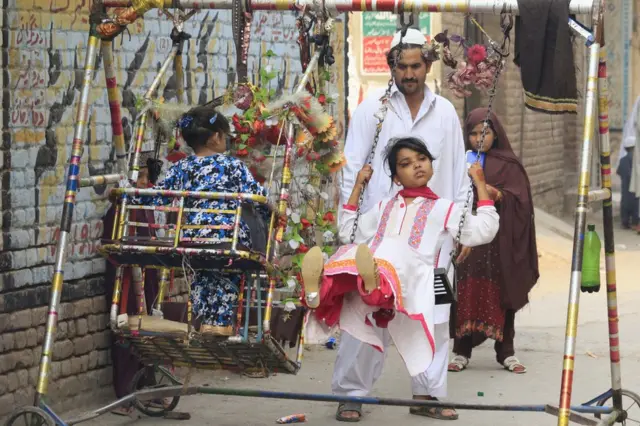 Children enjoy swings in Peshawar, Pakistan, 25 June