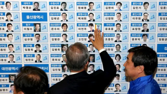 当選者の名前の横にシールを張る「共に民主党」の幹部ら(13日、ソウル)