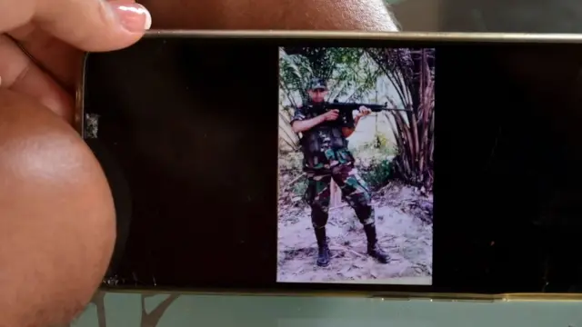 Florián y su esposa Angie muestran una foto de él cuando era soldado