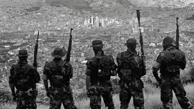 एंटिओकिया में मेडेलिन शहर को पहाड़ के ऊपर से देखते हुए अर्द्धसैनिक बलों के लोग