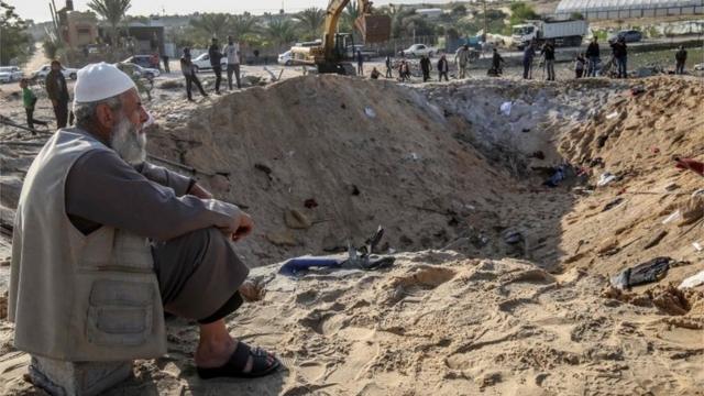 فلسطيني يجلس قرب حفرة سببتها الغارة الإسرائيلية الجوية على دير البلح