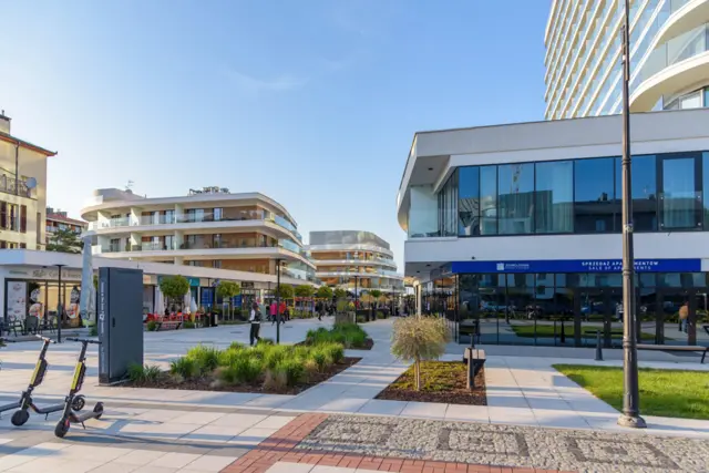 سائحون يمشون في متنزه الواجهة البحرية ببلدة شفينو أويتشه في يوم مشمس من أيام مايو/أيار 2022