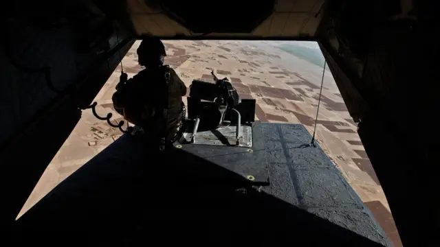 A soldier mans his position at the rear of a British helicopter as it is flown over the Helmand province of Afghanistan on August 31, 2010. (Photo credit should read ANDREW WINNING/AFP/Getty Images)