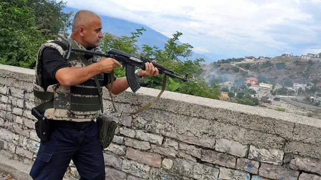 Homem branco segura um rifletruques de roletauma sacada