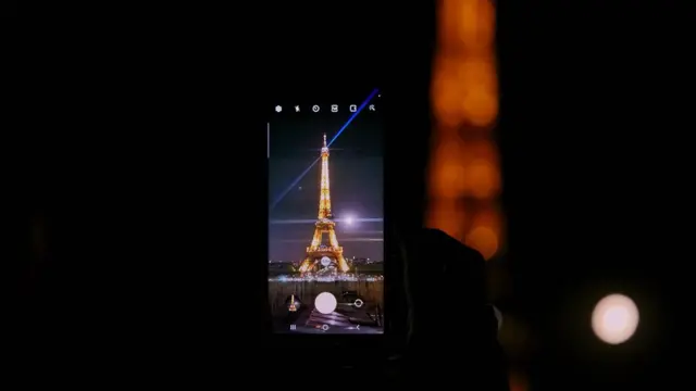 Спостерігач знімає на смартфон Місяць на тлі Ейфелевої вежі у Парижі