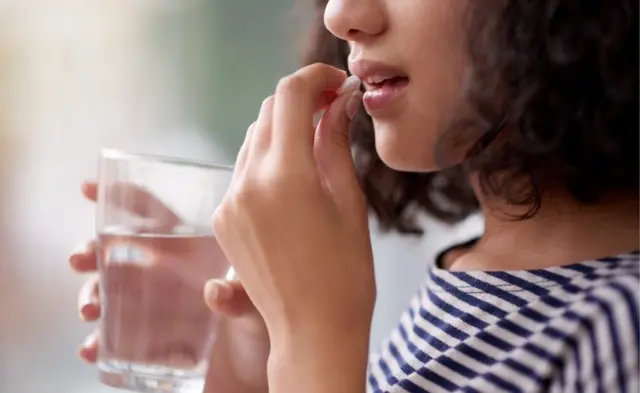 Mujer toma píldora.