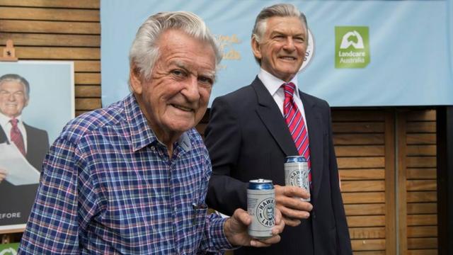 霍克2017年88岁生日，拿着以他命名的啤酒品牌Hawke's Lager，与同样拿着啤酒的霍克蜡像模型合照。