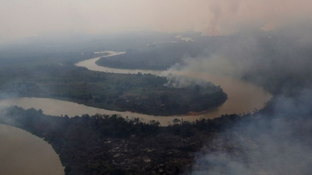 Vista aérea de rio no Pantanal, com florestas nas margens pegando fogo