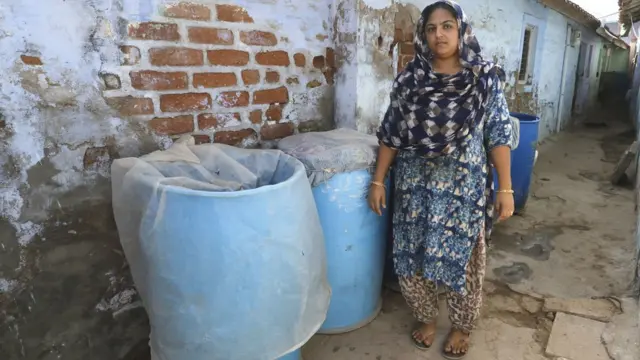 પાણીના બેરલ પાસે ઊભેલી મહિલા