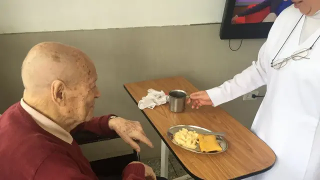 Un anciano frente a una mesa de comida