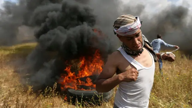 A Palestinian runs during clashes with Israeli troops, during a tent city protest along the Israel border with Gaza