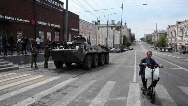 A man on a bike rides past a Wagner tank in Rostov-on-Don