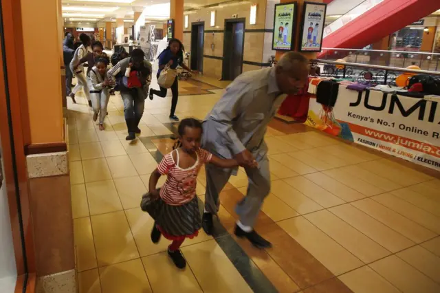 People with children run for safety as armed police hunt gunmen who went on a shooting spree at Westgate shopping centre in Nairobi, September 21, 2013.