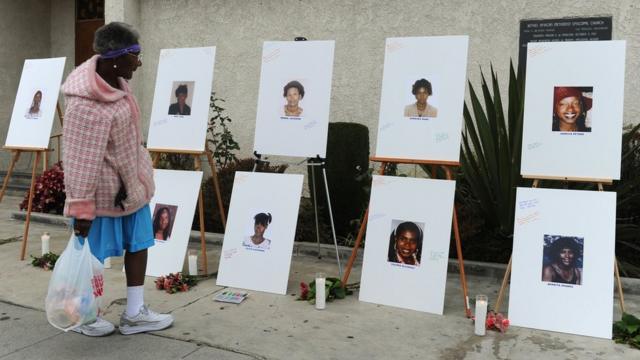 A woman views photographs set up as a memorial for 10 of the victims of the serial killer dubbed the 'Grim Sleeper'