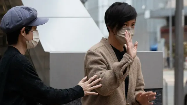 香港西區警署外《立場新聞》前董事何韻詩（右）向媒體記者揮手致意（30/12/2021）