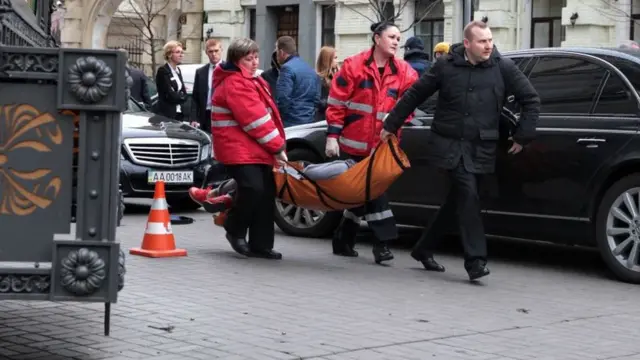 Предполагаемого убийцу несут к скорой помощи