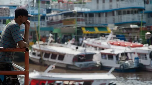 Joven mirando los barcos en el puerto de Manaos.