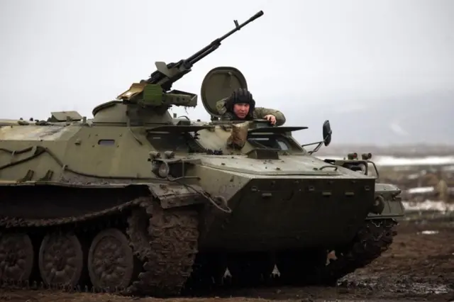 Российский военный на МТЛБ с крупнокалиберным пулеметом во время учений в Ростовской области