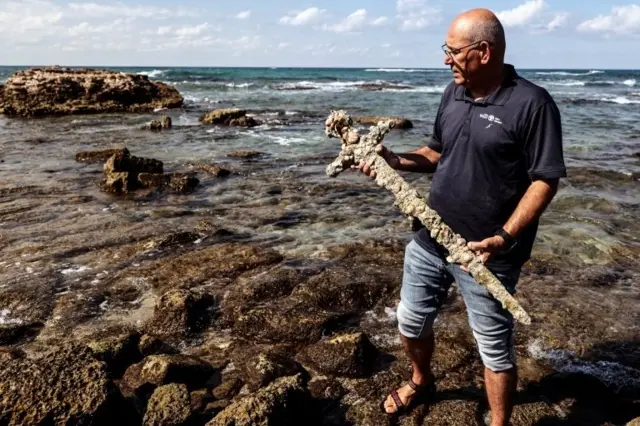 Yaakov Sharvit of the IAA holds a sword believed to have belonged to a Crusader who sailed to the Holy Land almost a millennium ago after it was recovered from the Mediterranean seabed by an amateur diver, the Israel Antiquities Authority said, Caesarea, Israel October 18, 2021