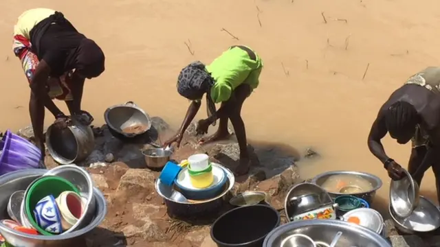 Children dey wash plates ontop flood water