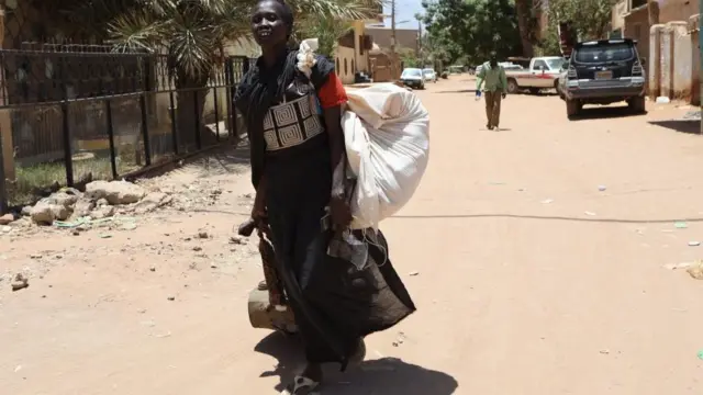 Une femme soudanaise porte ses affaires dans une rue de Khartoum, au Soudan, le 19 avril 2023.