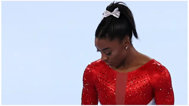 Simone Biles olha para baixo parecendo decepcionada