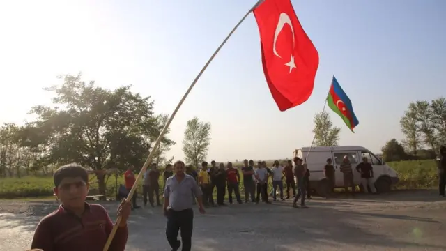 আজারবাইজানের লোকজন তুরস্কের পতাকা হাতে সৈন্যদের স্বাগত জানাচ্ছে।