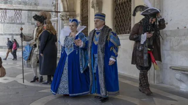 Туристы в костюмах на фоне стены