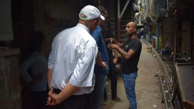 ధారావి మురికివాడ విశేషాలను పర్యటకులకు వివరిస్తున్న వ్యక్తి