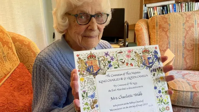 Betty Webb con la invitación a la coronación de Carlos III
