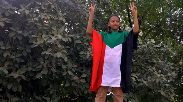 طفل تزينت بعلم السودان وتلوح بعلامة النصر