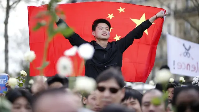 巴黎共和国广场悼念刘少尧集会现场的一名年轻华裔男子把中国国旗披在身上（2/4/2017）