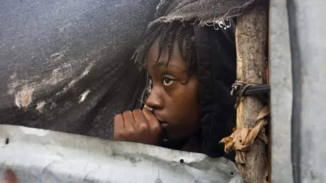 Msichana mdogo aangalia wakati maafisa walipofika kuondoa familia yake Tabarre, Haiti.