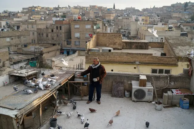 Resit Guzel, 55, feeds his pigeons on top of a roof