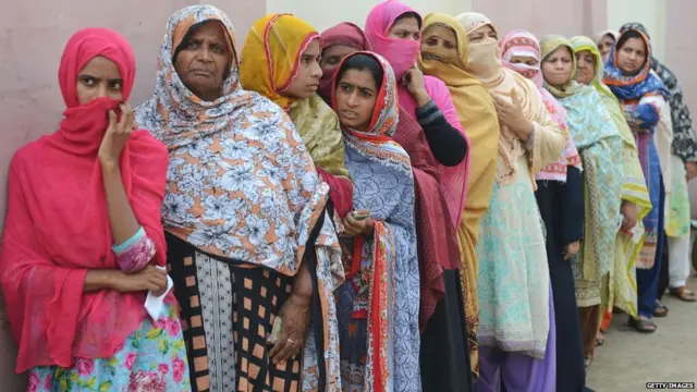 Pakistani women stand in a queue as they wait to cast their vote outside a polling station during general election in Lahore on July 25, 2018