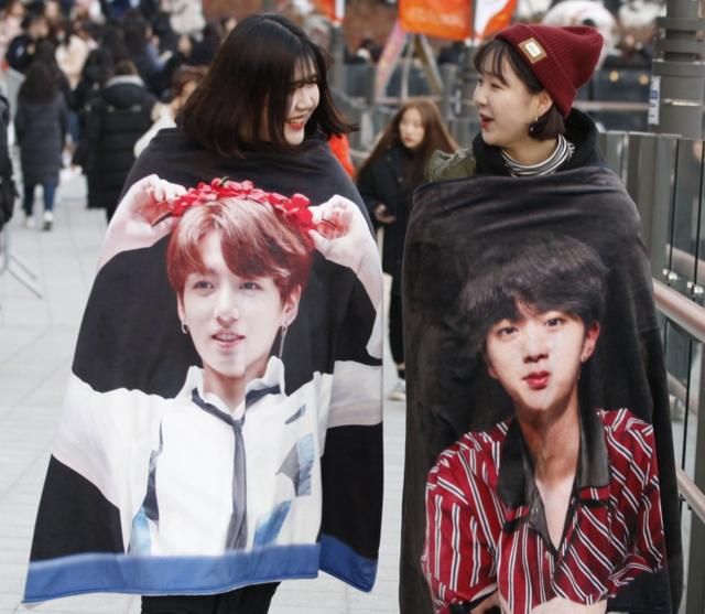 Fans of South Korean boy band BTS wearing coats of members Jungkook and Jin