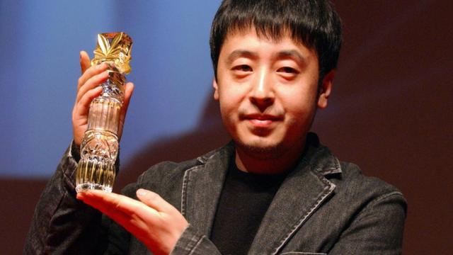 Chinese director Jia Zhang-Ke holds his trophy 13 March 2005 after winning the Lotus of the best screenplay with his film 'The World' , during the 7th Asian Film Festival in Deauville.