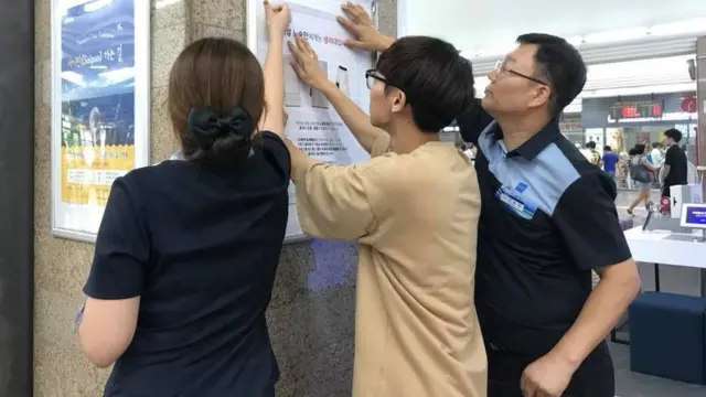 Jaeha Woo puts up posters about period poverty in Seoul station.