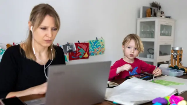 Mujer trabajando con su hijo al lado.