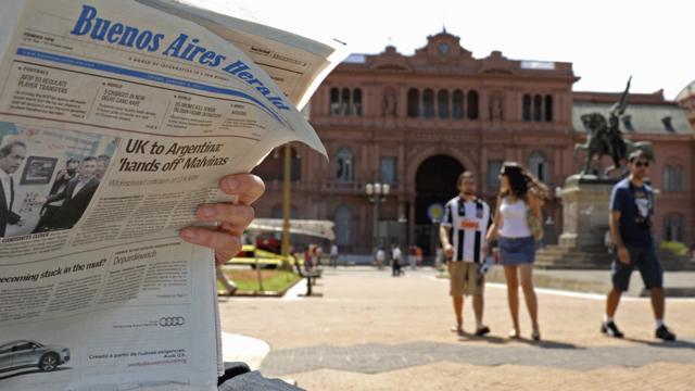 Lector leyendo el Buenos Aires Herald frente a la Casa Rosada en Plaza de Mayo.