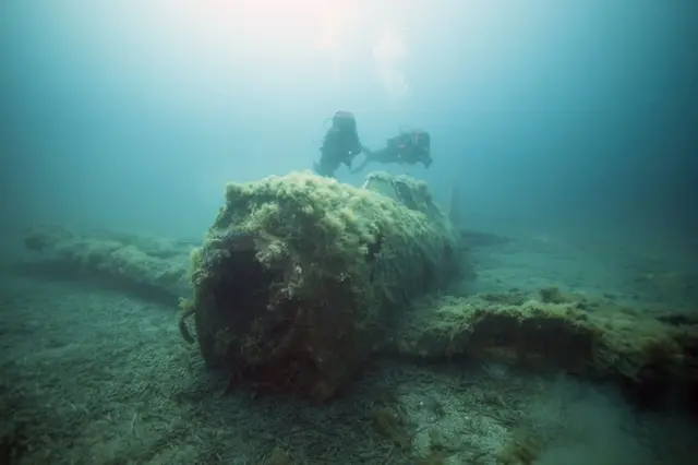 A French military diver member of the FS Pluton M622 navy de-mining ship, swims on July 2, 2018, above the wreck of an USAAF P-47 Thunderbolt (Warthog) US fighter plane