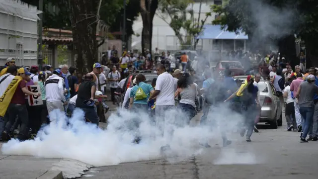 Opositores huyen de los gases lacrimógenos.