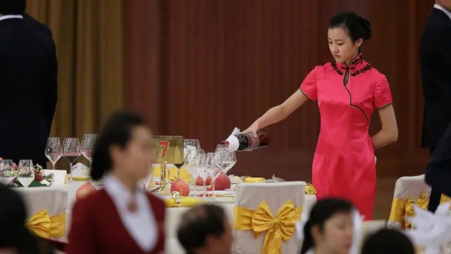 Mulher serve vinho durante um banquetecodigo betano hojePequim